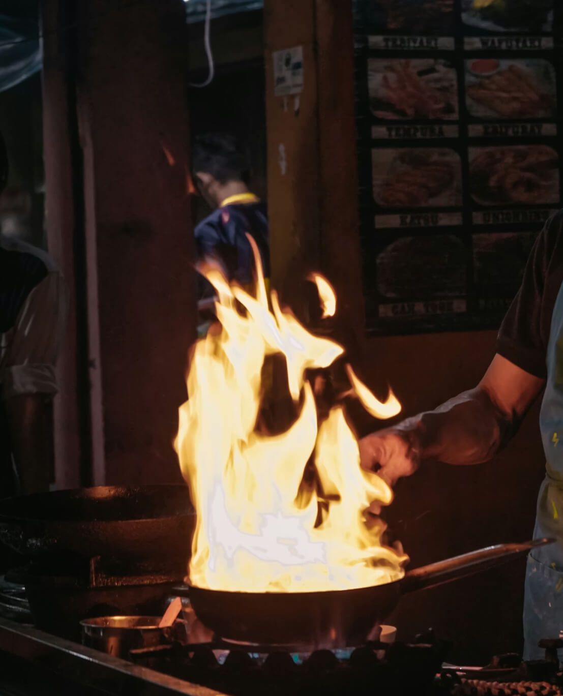 Chef cooking with dramatic flames in a traditional wok